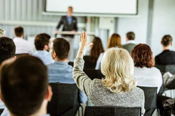 A businesswoman raising her hand to ask a question during an interactive meeting