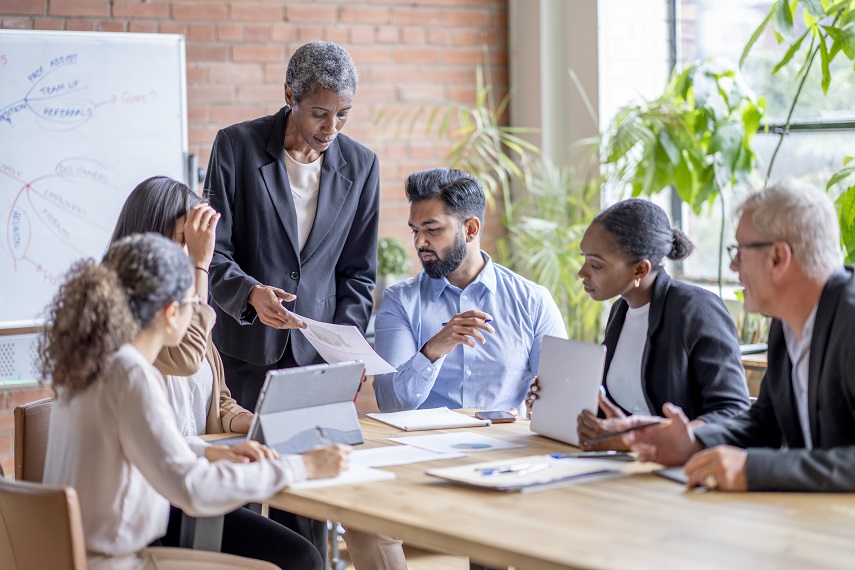 Executive leading a discussion with colleagues around a conference table