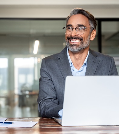 Smiling businessman working at laptop in modern office
