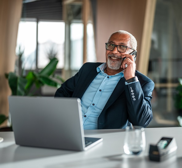 A mature businessman smiles while talking on a phone